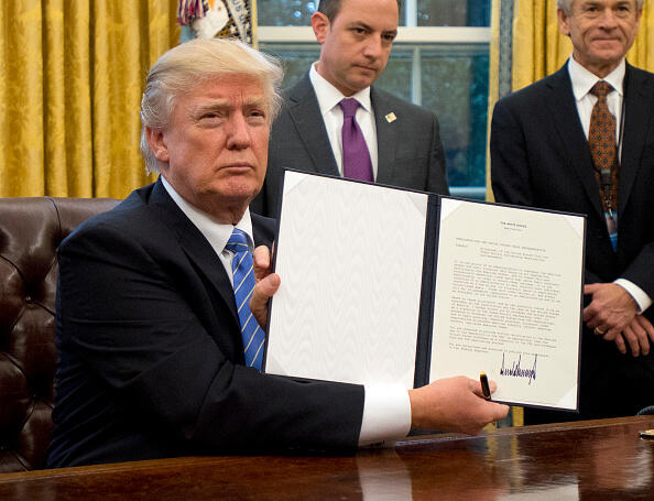 WASHINGTON, DC - JANUARY 23:  (AFP OUT) U.S. President Donald Trump shows the Executive Order withdrawing the US from the Trans-Pacific Partnership (TPP) after signing it in the Oval Office of the White House in Washington, DC on Monday, January 23, 2017.  The other two Executive Orders concerned a US Government hiring freeze for all departments but the military, and 