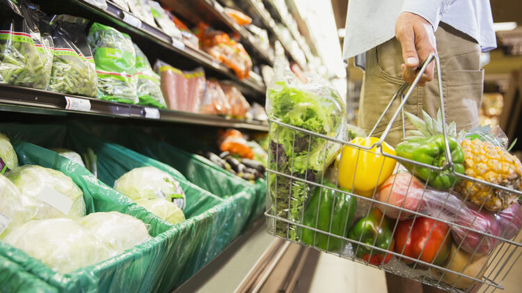 Man carrying full shopping basket in grocery store