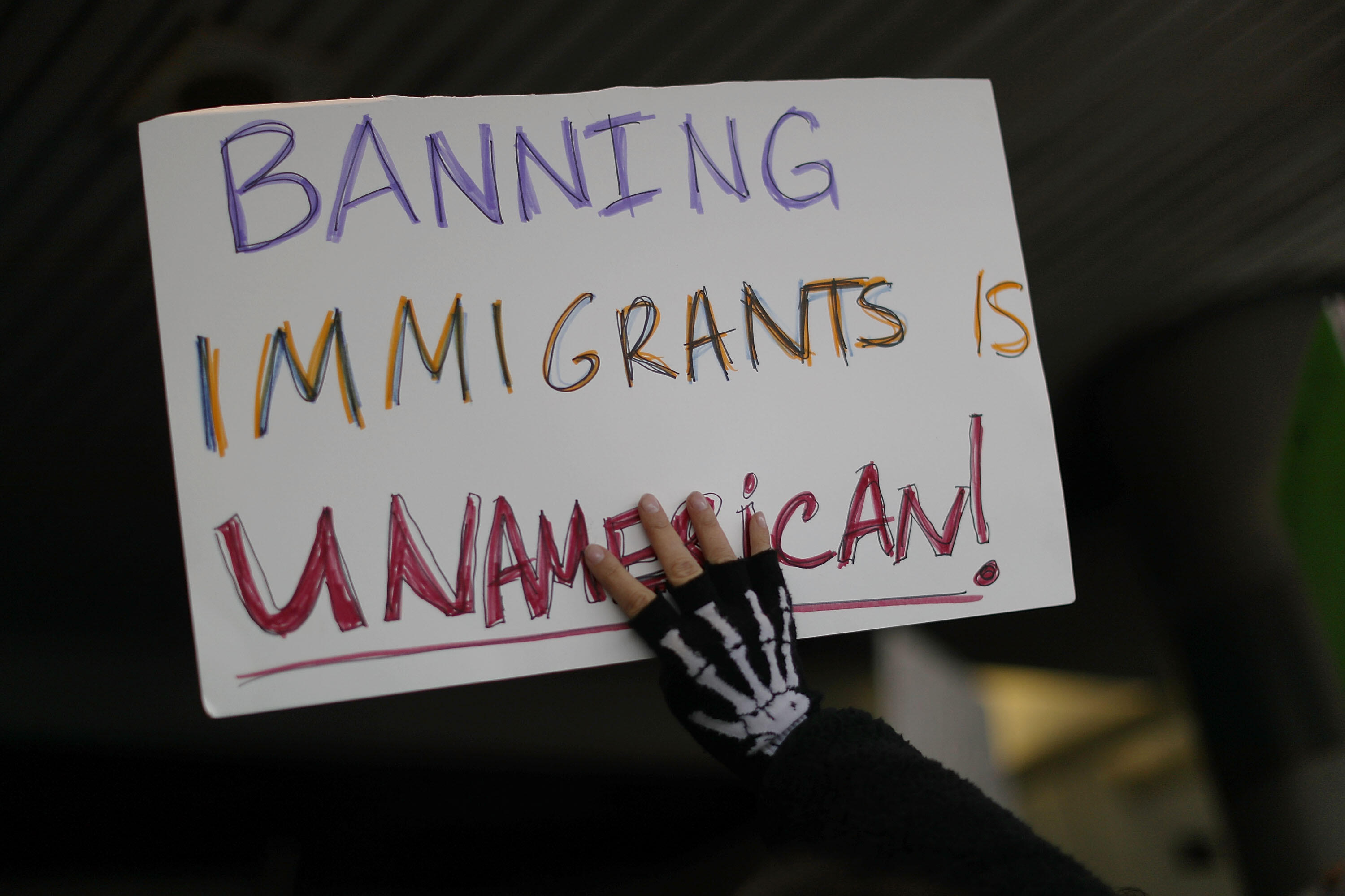 MIAMI, FL - JANUARY 29: A protester holds up a sign that reads, 'Banning Immigrants is UnAmerican!,' as she  stands with others at the Miami International Airport against the executive order that President Donald Trump signed  clamping down on refugee adm