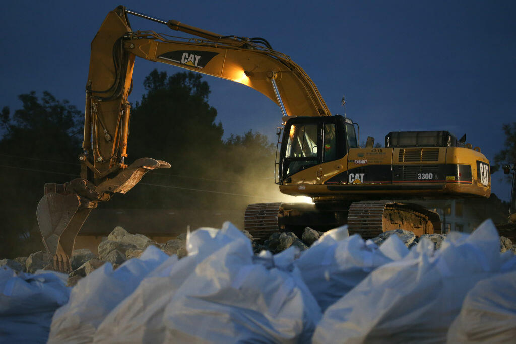 OROVILLE, CA - FEBRUARY 13: A backhoe collects boulders to load into a dump truck as bags of rocks await pickup by helicopters  at Oroville Lake on February 13, 2017 in Oroville, California. Almost 200,000 people were ordered to evacuate the northern California town after a hole in the emergency spillway in the Oroville Dam threatened to flood the surrounding area.  (Photo by Elijah Nouvelage/Getty Images)