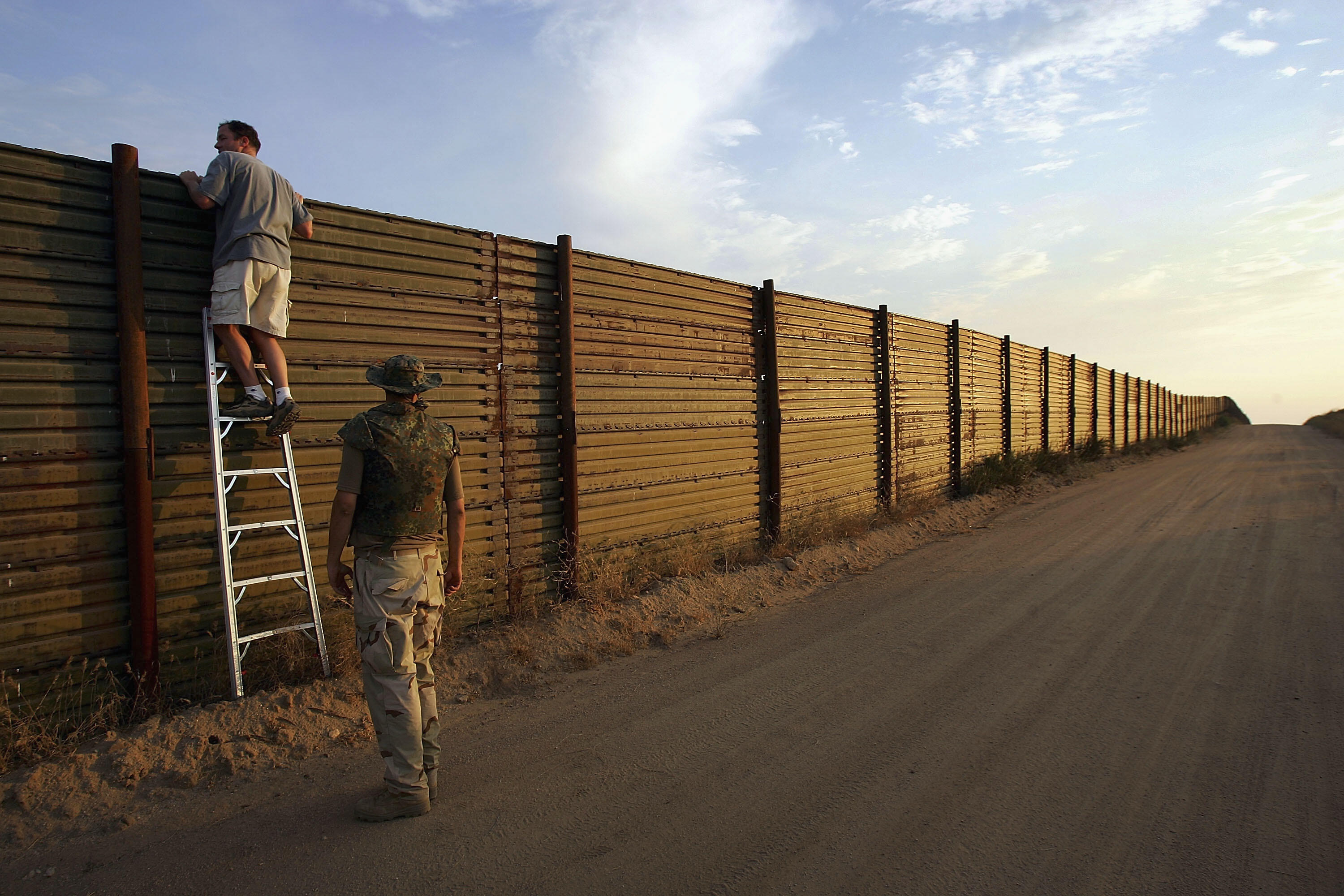 CAMPO, CA - JULY 19:  Volunteers look over the US-Mexico border fence to see how illegal border crossers may jump the fence before going on the nightly patrol by citizen volunteers searching for people crossing into the US illegally from Mexico on July 19