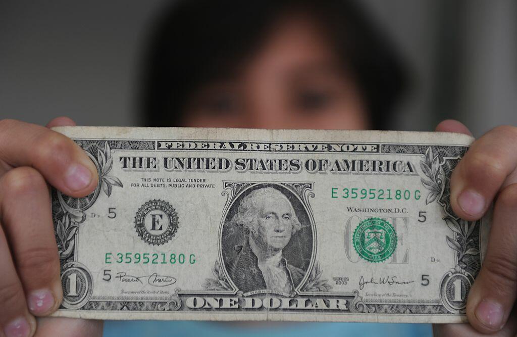 A person holds a one dollar bill on December 18, 2011 in San Jose, Costa Rica. Apart of the local currency, colones, dollars are also used in Costa Rica. AFP PHOTO/ Rodrigo ARANGUA (Photo credit should read RODRIGO ARANGUA/AFP/Getty Images)