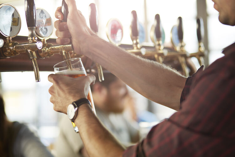 Close-up of bartender making cask beers at bar