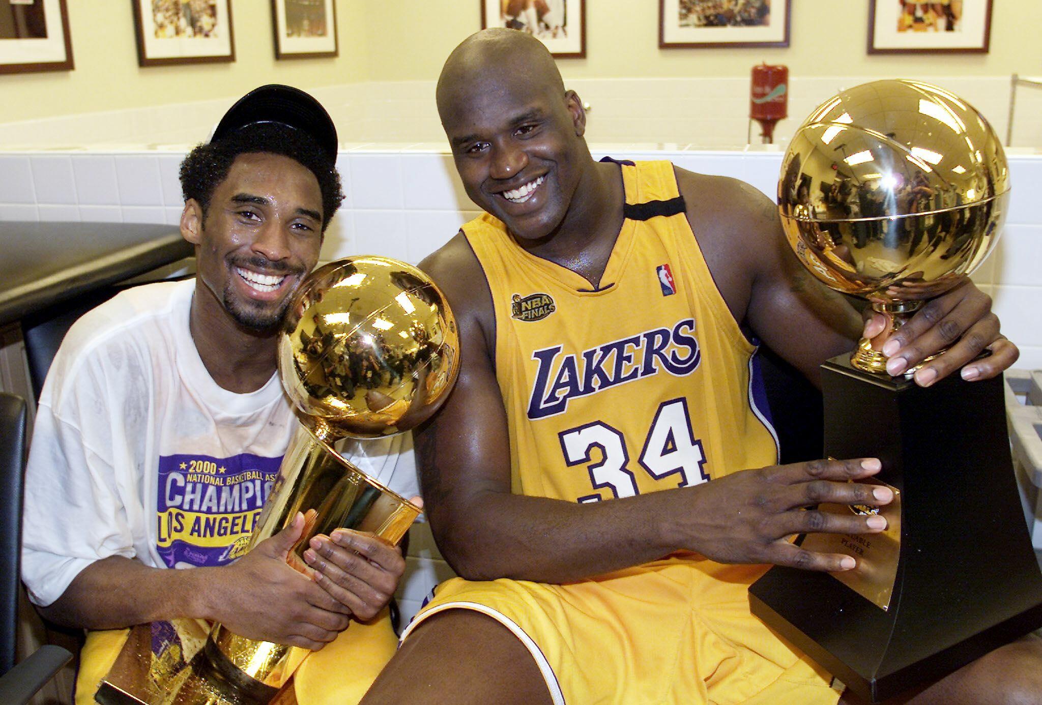 LOS ANGELES, UNITED STATES:  Kobe Bryant (L) of the Los Angeles Lakers holds the Larry O'Brian trophy as teammate Shaquille O'Neal (L) hold the MVP trophy after winning the NBA Championship against Indiana Pacers 19 June, 2000, after game six of the NBA F