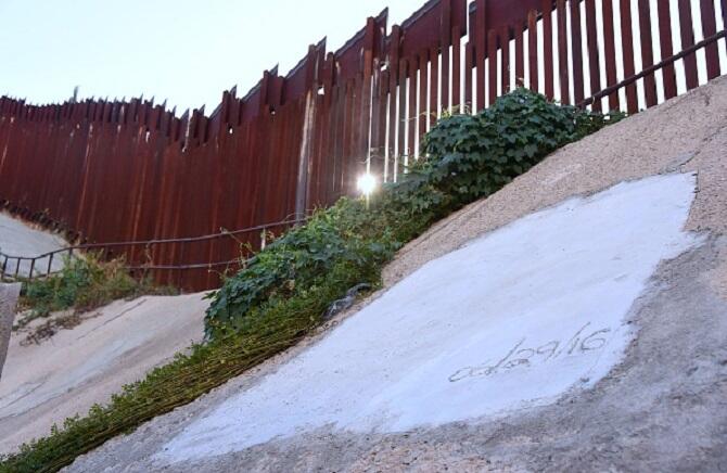 The morning sun breaks through the US-Mexico border fence as a cement block covers what once was a tunnel near the Morley Gate Border Station in Nogales, Arizona on October 13, 2016.   Since discovering the first drug tunnel in nearby Douglas, Arizona in 