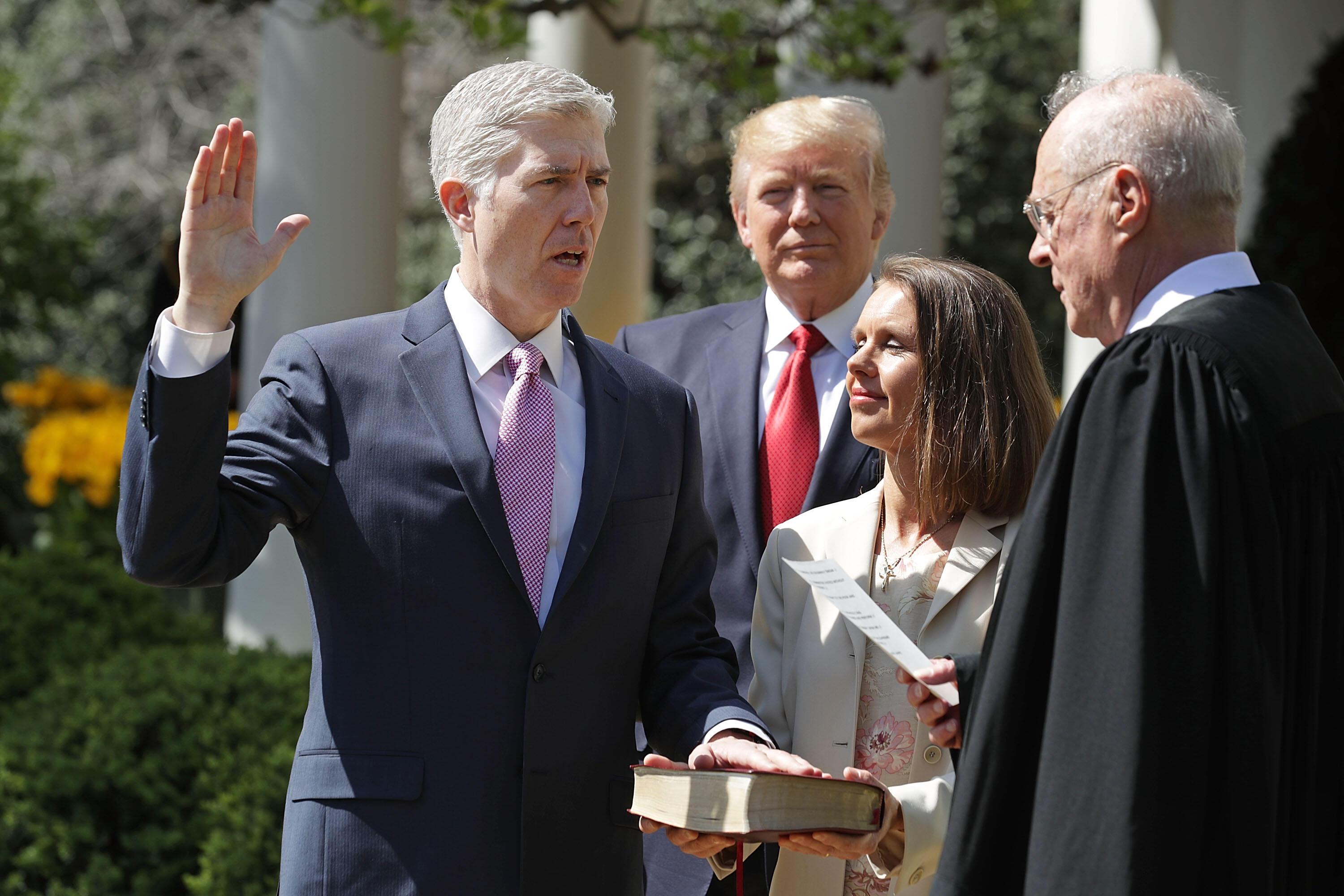 WASHINGTON, DC - APRIL 10:  U.S. Supreme Court Associate Justice Anthony Kennedy (R) administers the judicial oath to Judge Neil Gorsuch (L) as his wife Marie Louise Gorshuch holds a bible and President Donald Trump looks on during a ceremony in the Rose 