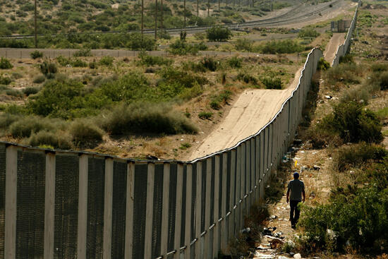 CIUDAD JUAREZ, CHIHUAHUA - JUNE 29:  A man walks along the border fence between the U.S. and Mexico on June 29, 2007 in the Anapra area of Ciudad Juarez, Mexico. This area is a popular crossing spot for immigrants to ilegally cross into the United States 