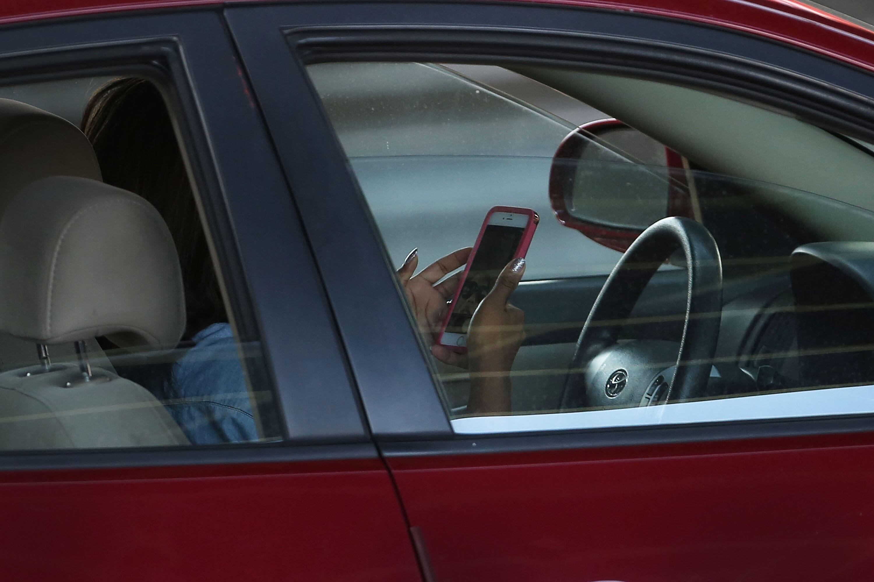 NEW YORK, NY - APRIL 30: A driver uses a phone while behind the wheel of a car on April 30, 2016 in New York City. As accidents involving drivers using phones or other personal devices mount across the country, New York lawmakers have proposed a new test 