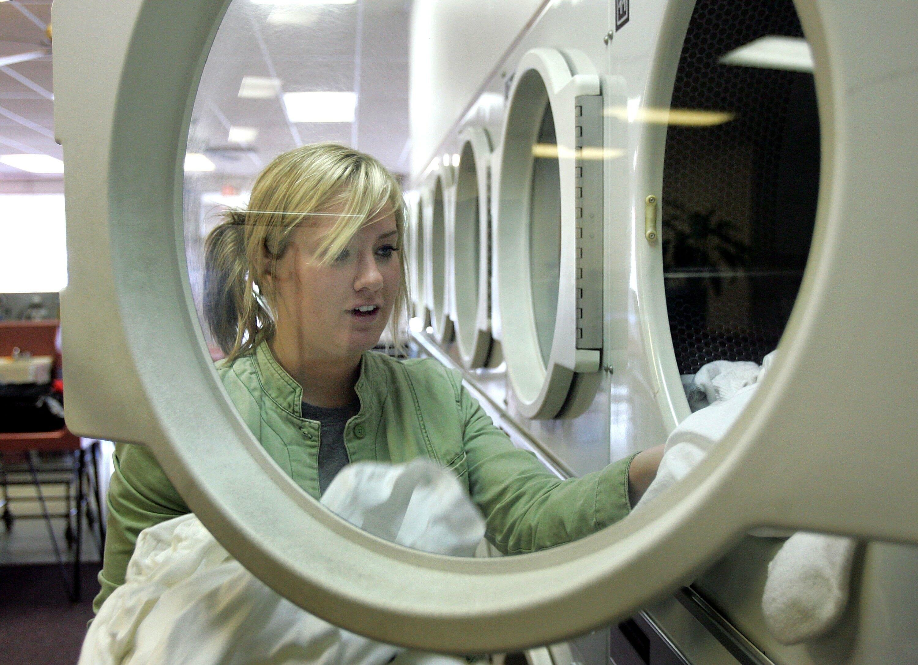 MOUNT PROSPECT, IL - MAY 11:  Katie Reynolds pulls out clothing from a Maytag commercial dryer at a Maytag laundromat May 11, 2006 in Mount Prospect, Illinois. Whirlpool reportedly may be closing three Maytag manufacturing plants and offices as well as el