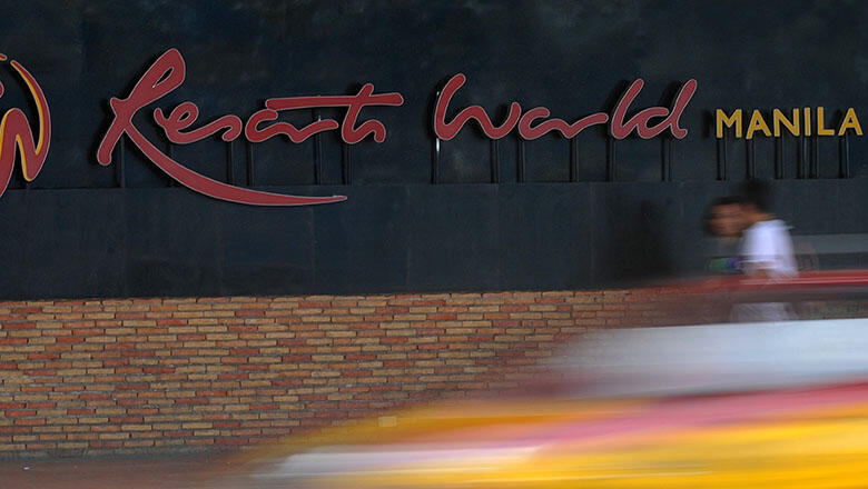 Pedestrians walk in front of Resorts World Manila logo on August 14, 2015. The owner of the Philippines' first mega-casino Resorts World on August 14, said its second-quarter profits halved amid an industry wide slump that could threaten the country's bid