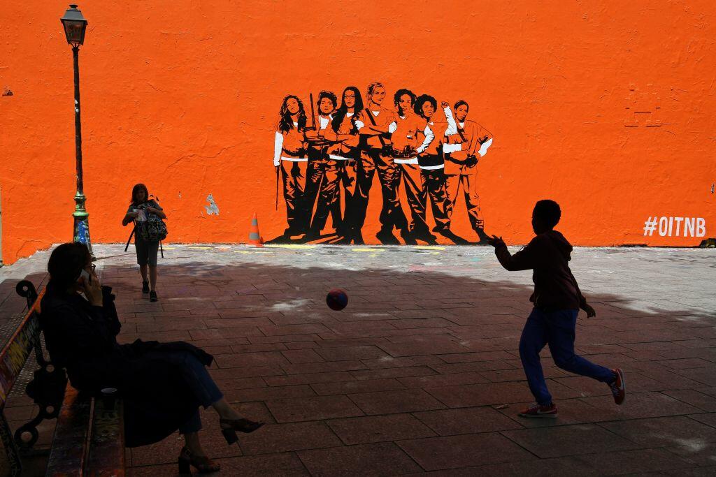 A boy plays football by a mural painting depicting the upcoming US series 