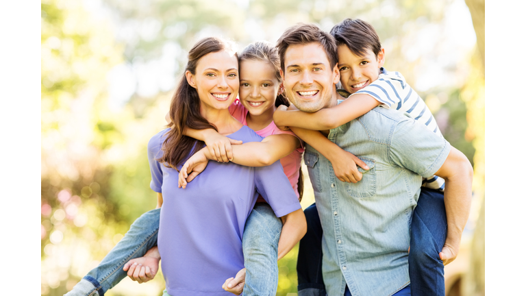 Happy Children Enjoying Piggyback Ride On Parents