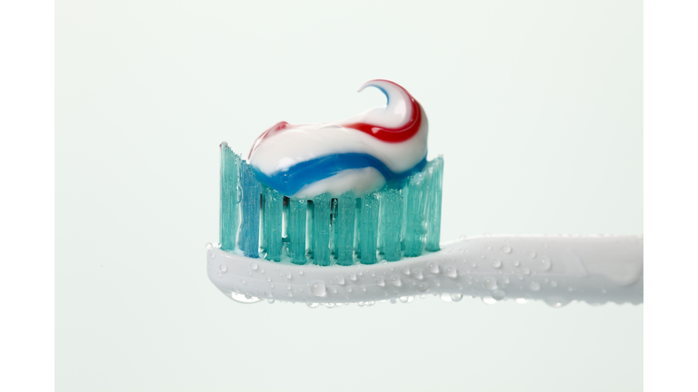 Electric toothbrush with toothpaste against white background, close up