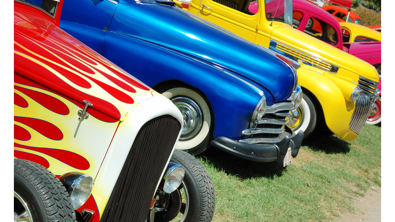 Line of hotrod cars in grass at car show