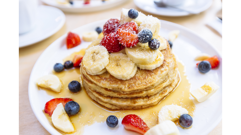 Close-up of delicious pancakes with fresh fruits, berries and maple syrup on a plate