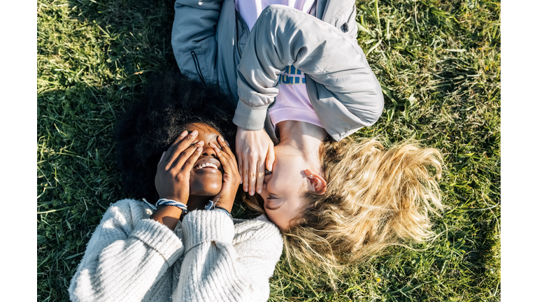 Two best friends telling secrets lying in the grass