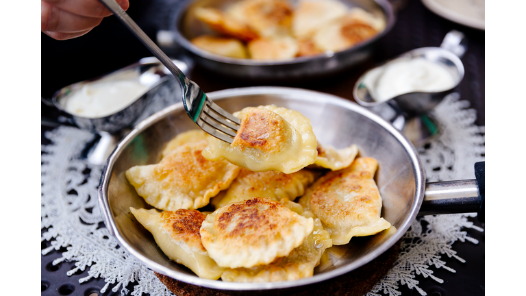 Eating traditional Polish dumplings Pierogi with fork