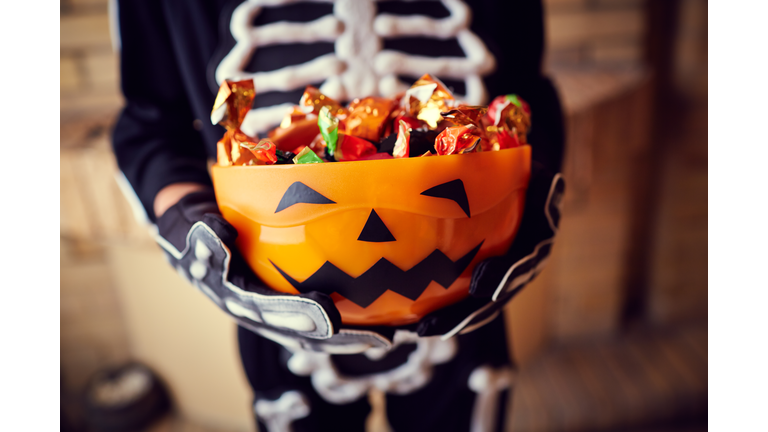 Boy in skeleton costume holding bowl full of candies