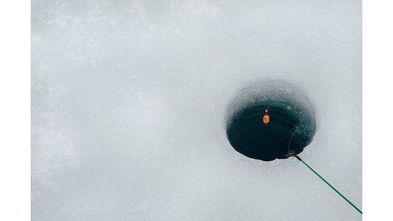 High Angle View Of Fishing Rod Over Hole In Frozen Lake