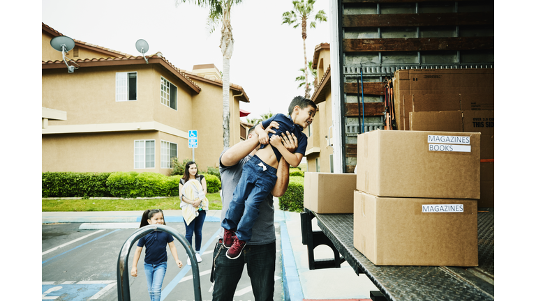 Father lifting smiling son into back of moving truck