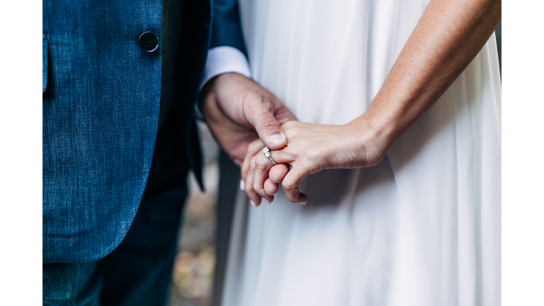 Midsection Of Newlywed Couple Holding Hands