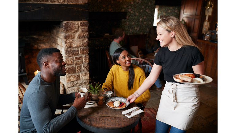 Waitress Working In Traditional English Pub Serving Breakfast To Guests