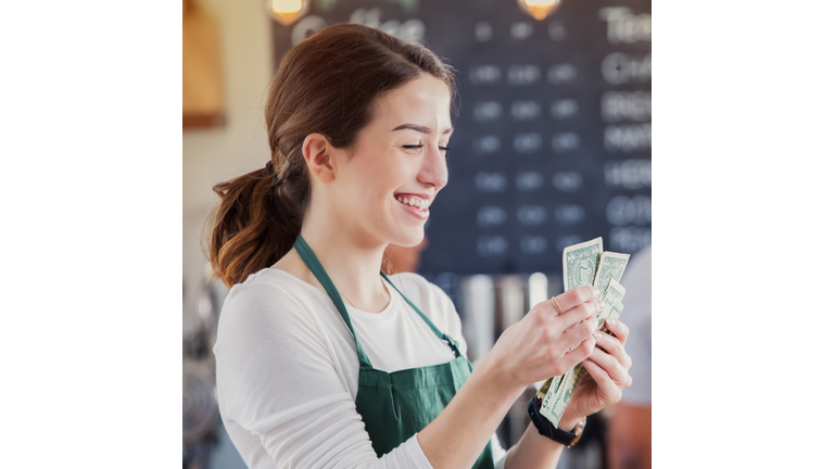 Cheerful female barista counts her tips