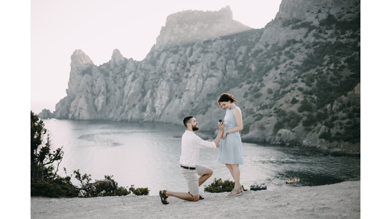 Caucasian man proposing marriage to woman at beach