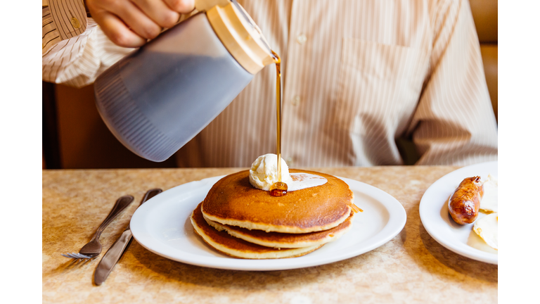 Man pouring maple syrup over pancakes in the diner