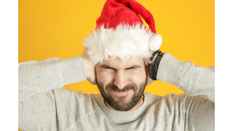 Portrait of annoyed man wearing santa hat, studio shot. Deaing with winer holiday stress concept.