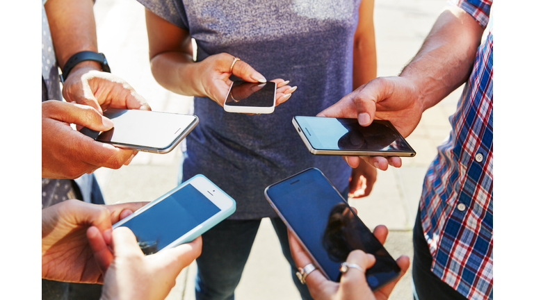 5 friends with smartphones, close up.