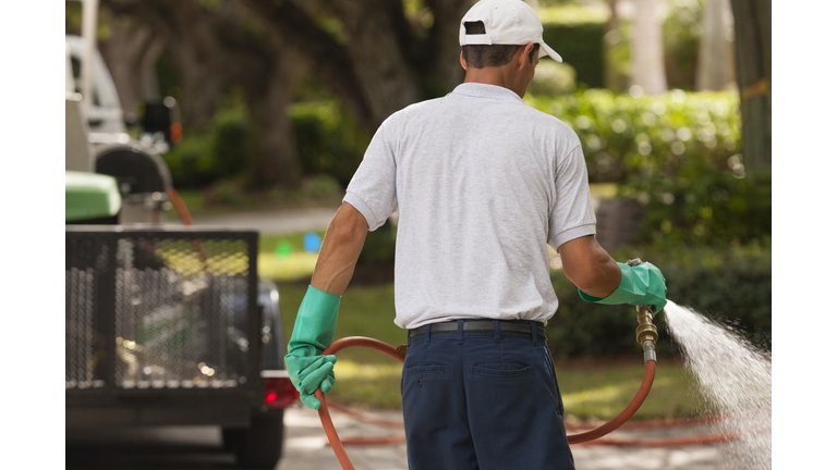 Pest control technician using high pressure spray gun with heavy duty gloves