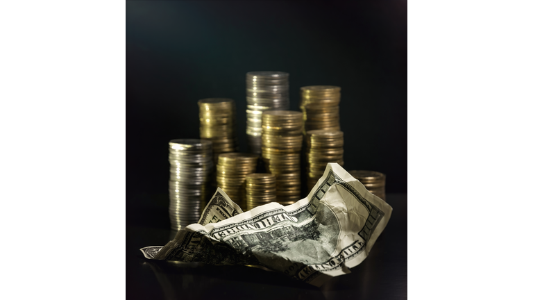 Piles of coins of various denominations on a black background and a crumpled hundred dollar bill . Investments and Savings