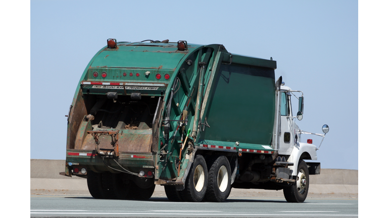 A garbage truck driving along an open road