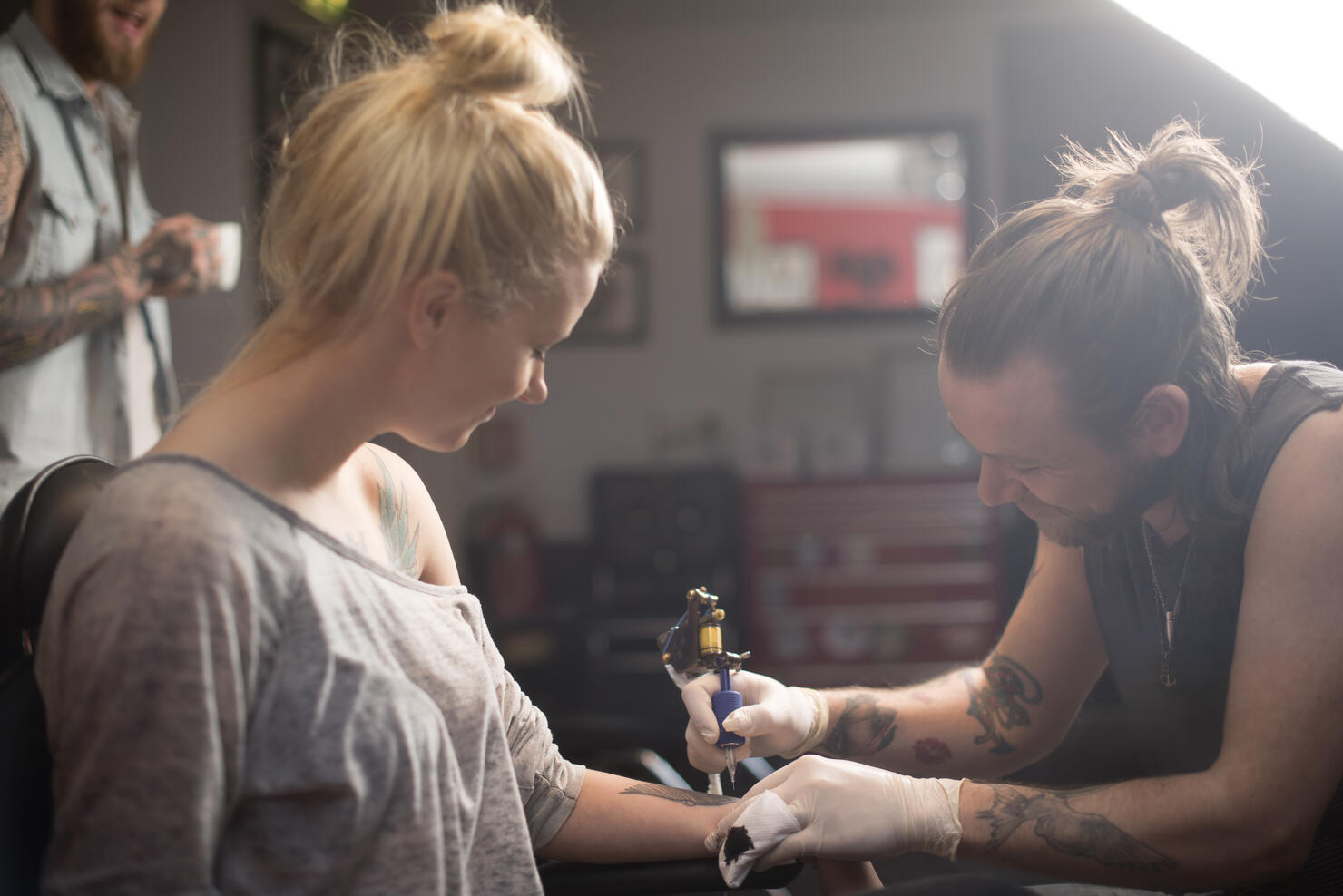 Artist making tattoo on female customer's hand