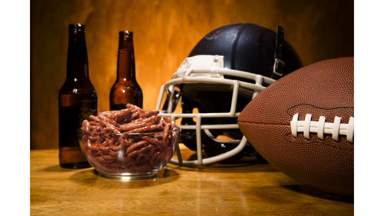 Sports:  Football helmet, ball on table.  Pretzels and beer. Superbowl.
