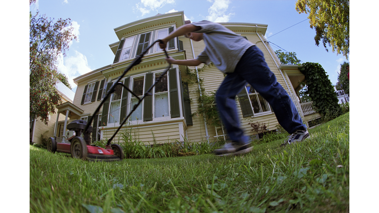 BOY MOWING LAWN IN FRONT OF HOUSE