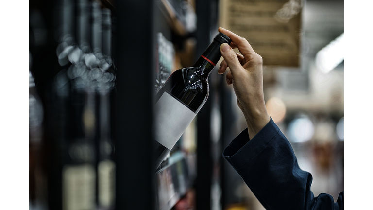 Woman choosing wine bottle in liquor store