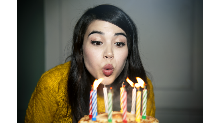 Mixed race woman blowing out birthday candles
