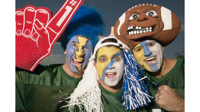 Three male football fans wearing face paint, gesturing