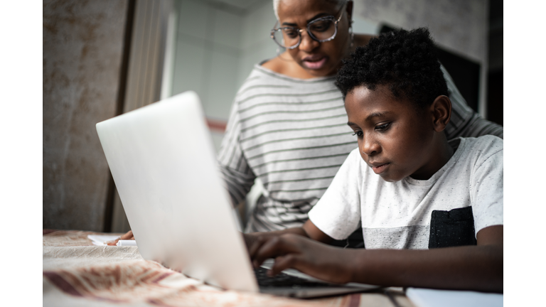 Mother helping son studying with laptop on a online class at home