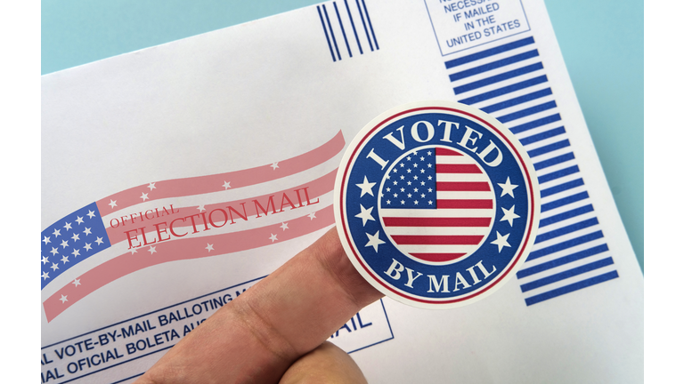 Human finger holding sticker above voting mail