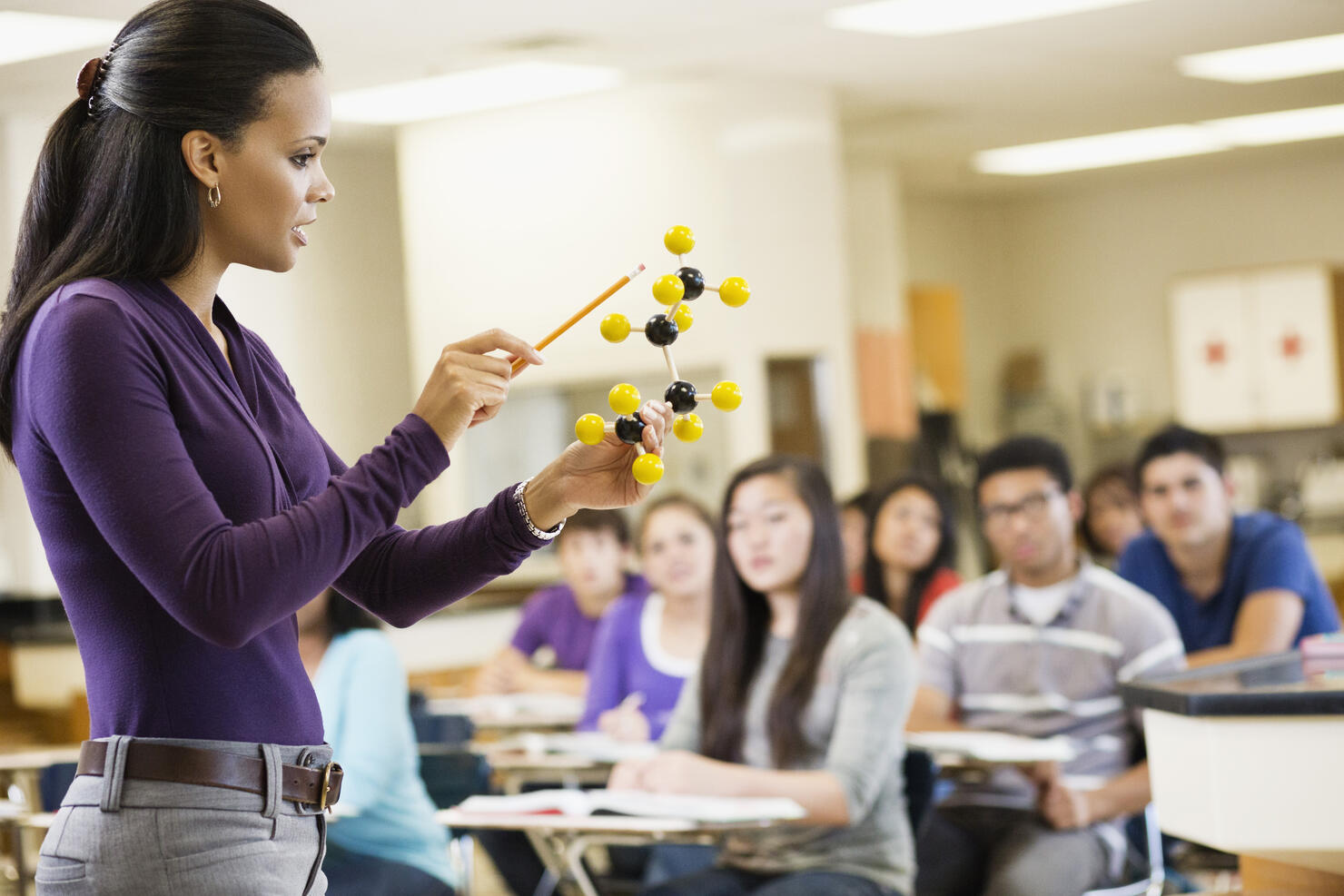 Teacher explaining chemistry model to classroom