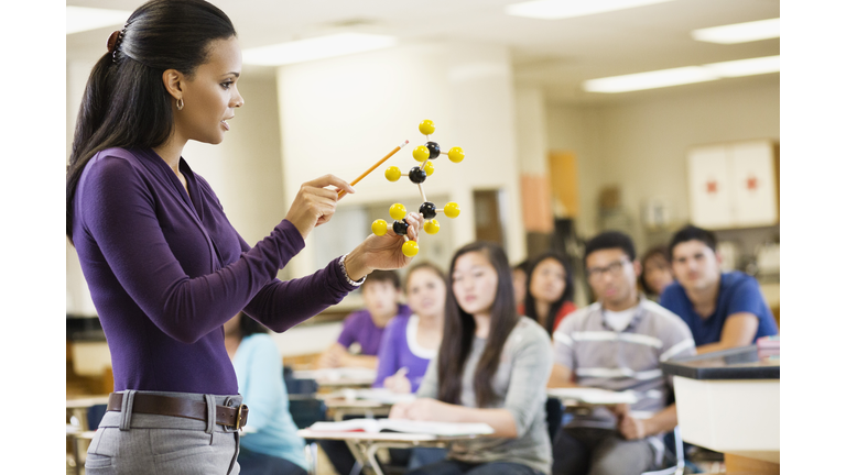 Teacher explaining chemistry model to classroom