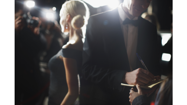 Celebrity signing autographs on red carpet