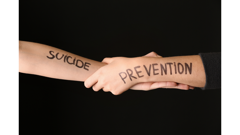 Female hands with text SUICIDE PREVENTION on dark background