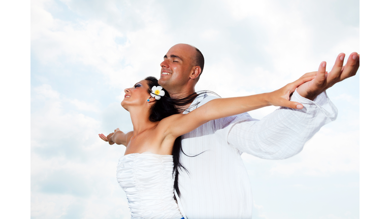 Beautiful married couple against the sky.