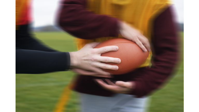 Close up of a hand off of a football in a game of non-contact flag football.