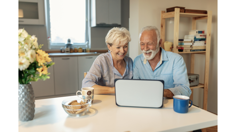 Mature couple browsing the internet and buying. Online shopping.