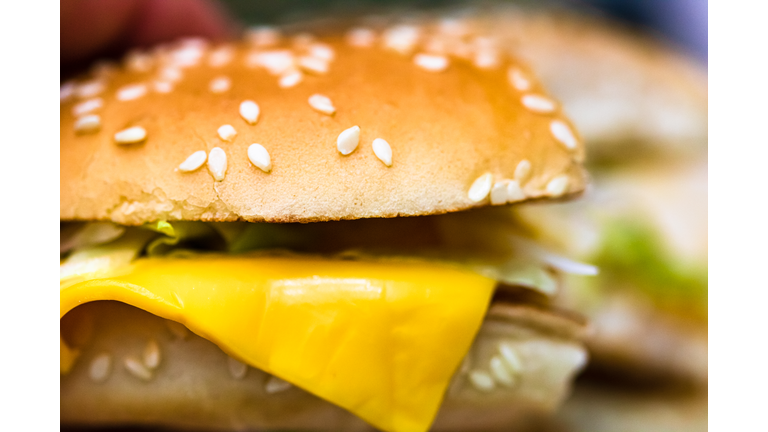 Close up detail of a bitten cheeseburger. Food, junk food and fast food concept